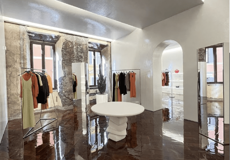 White brick room with orange and black clothing hanging from racks. 